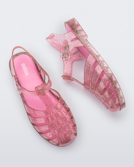 A top and side view of a pair of pink glitter Melissa Possession Shiny sandals with several straps and a closed toe front.