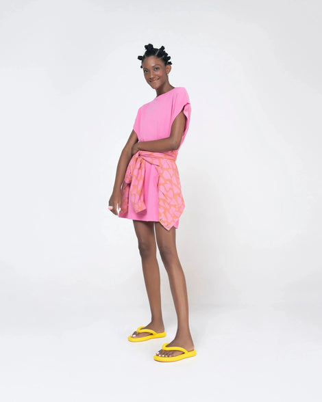 A model posing for a picture in a pink dress and yellow Melissa Free Flip Flops with puffer-like straps.