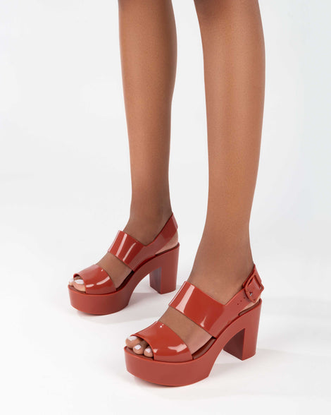 A model's legs wearing red Melissa Mule heel platform Sandals.