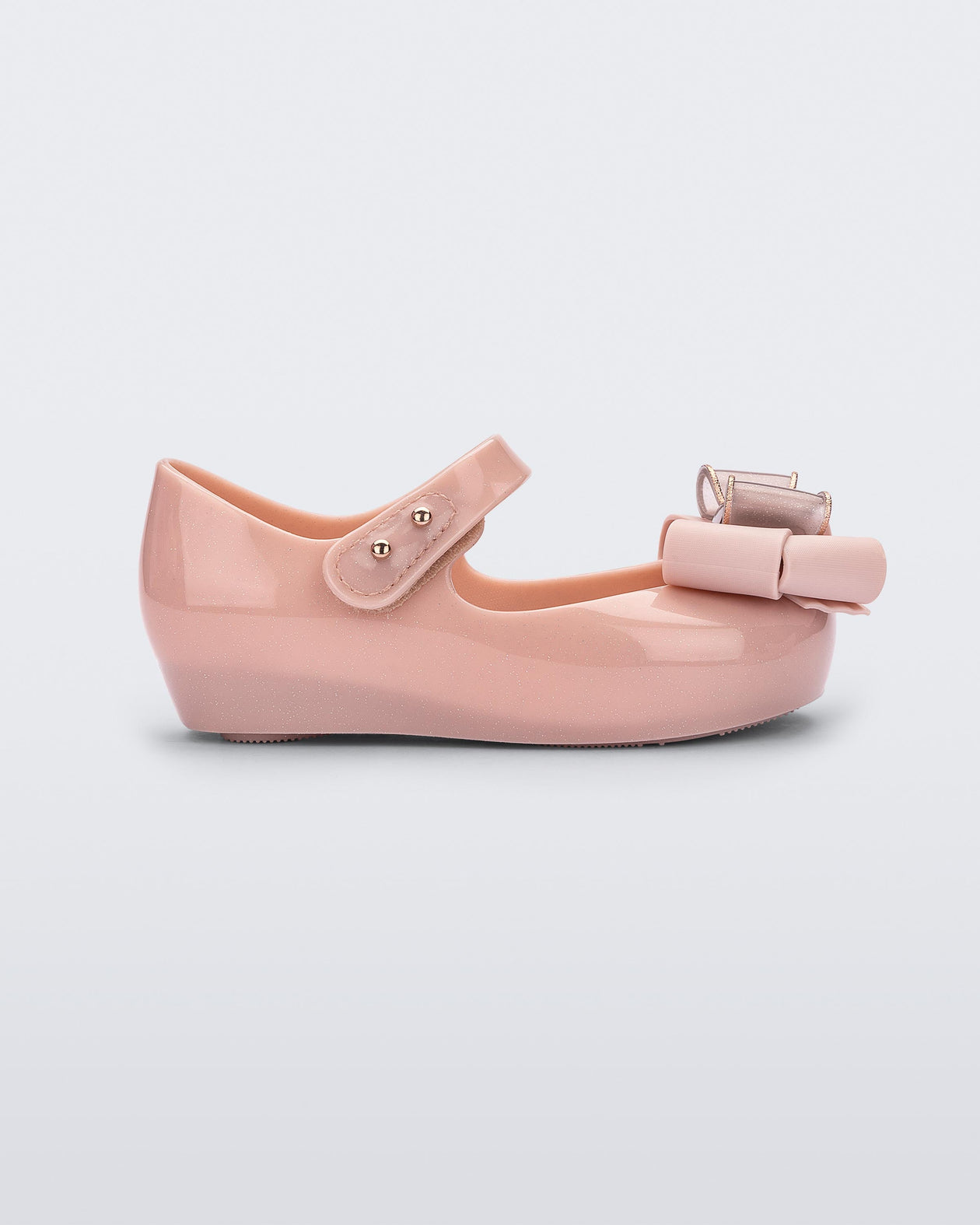 Side view of a Pink Glitter/Beige Mini Melissa Ultragirl Sweet flat with a top strap and bow detail on the toe.