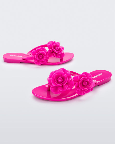 Side view of a pair of pink Mini Melissa Harmonic Garden flip flops with flowers on the straps.