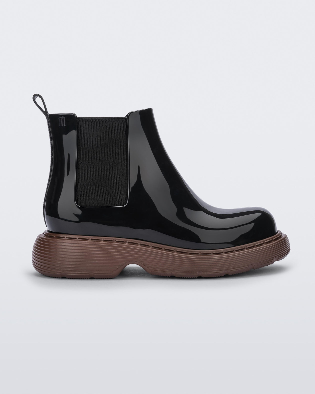 Side view of a Melissa Step slip on ankle boot with bronze sole and black upper.