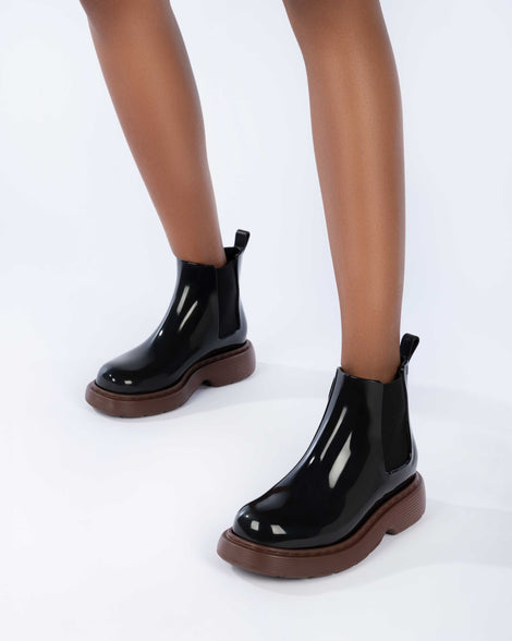 Model's legs wearing a pair of Melissa Step slip on ankle boots with bronze sole and black upper.