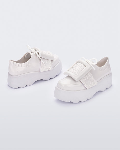 Angled view of a pair of white Melissa Buckle Up Kick Off platform sneakers.