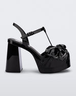 Side view of a black Melissa Tie Party Heel with several straps and a bow on the toe.