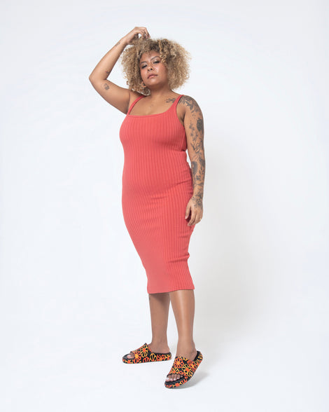 A model posing for a picture in a red dress and a pair of multicolor matte mosaic flower Melissa Cloud slides with a black base and an orange and yellow flower pattern.