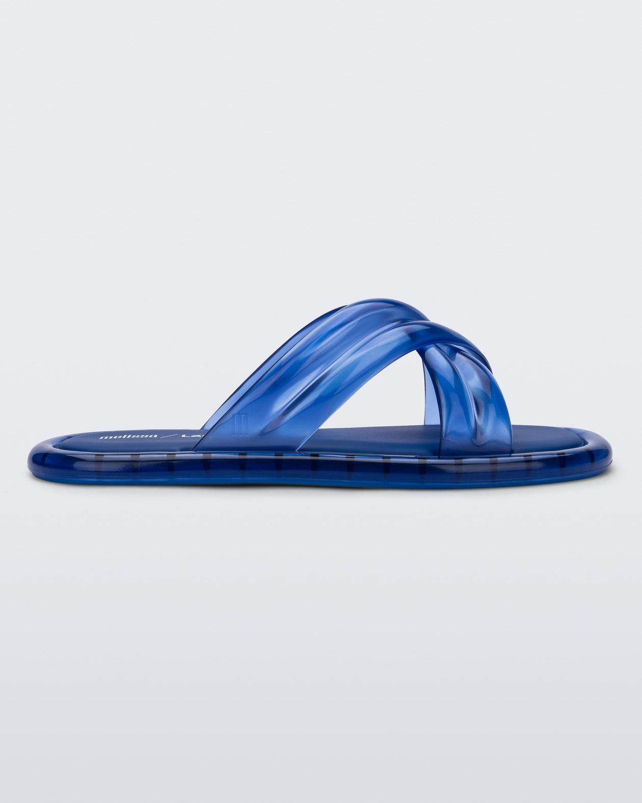 Side view of a transparent blue Melissa Cali slide with cross straps.