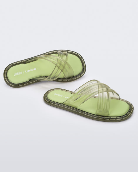 Top and side view of a pair of transparent green Melissa Cali slides with cross straps.