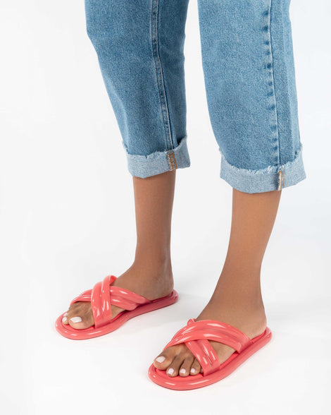 A model's legs wearing a pair of red Melissa Cali slides with cross straps.