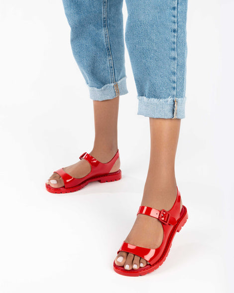 A model's legs wearing a pair of red Melissa Bae sandals.