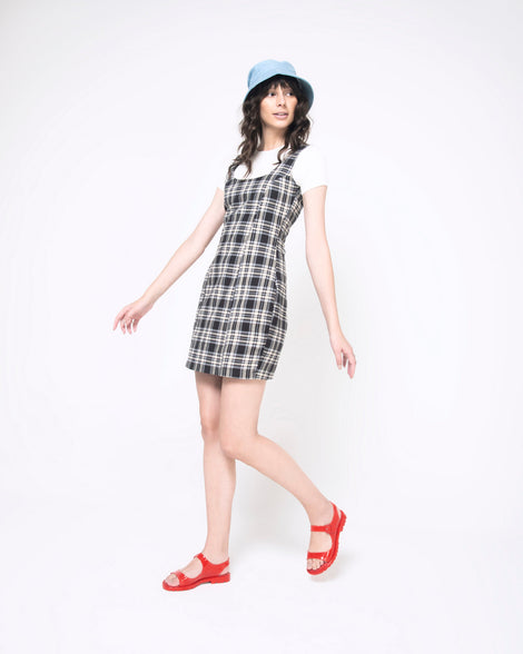 A woman in a plaid dress wearing a pair of red Melissa Bae sandals.