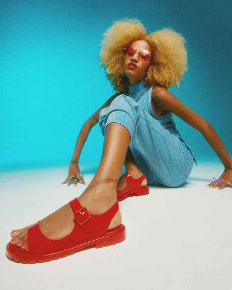 A model posing wearing a pair of red Melissa Bae sandals