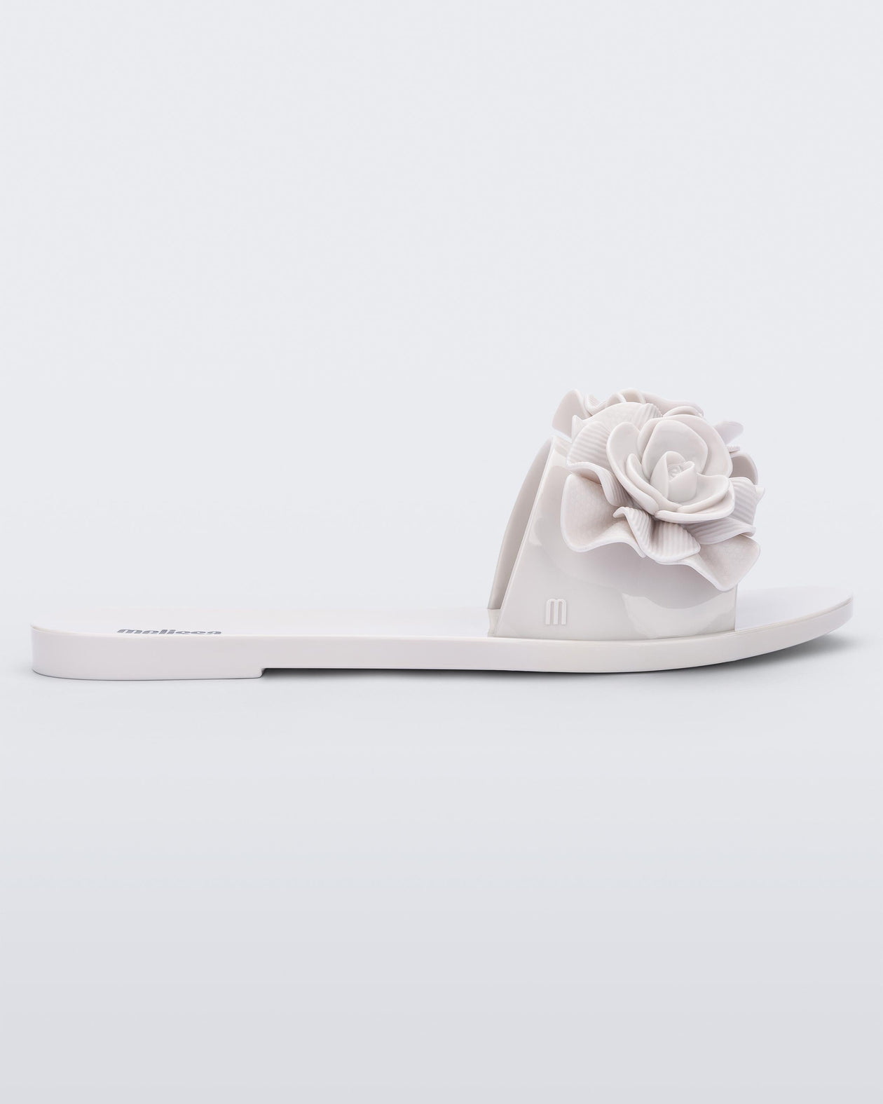 Side view of a white Melissa Babe Garden slide with two flowers on the front strap.