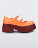 Side view of an orange Melissa Farah platform shoe, with a brown sole and two orange straps fastened by orange buckles.