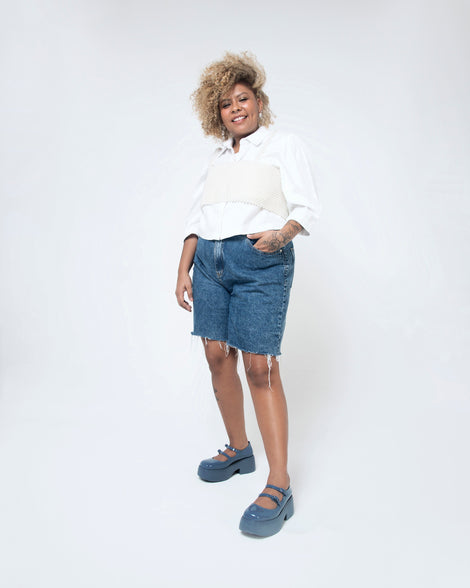 A model posing for a picture wearing a pair of blue Melissa Farah platform shoes with two straps fastened by blue buckles.