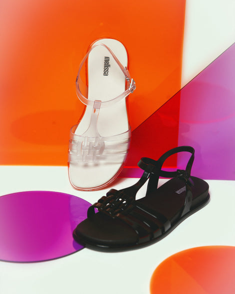 Two Melissa Party Sandals, one clear and one black, both with back ankle straps and buckle closures.