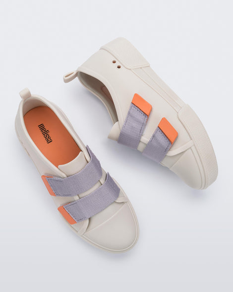 A top and side view of a pair of matte beige/lilac Melissa Cool sneakers with two orange and lilac velcro straps.