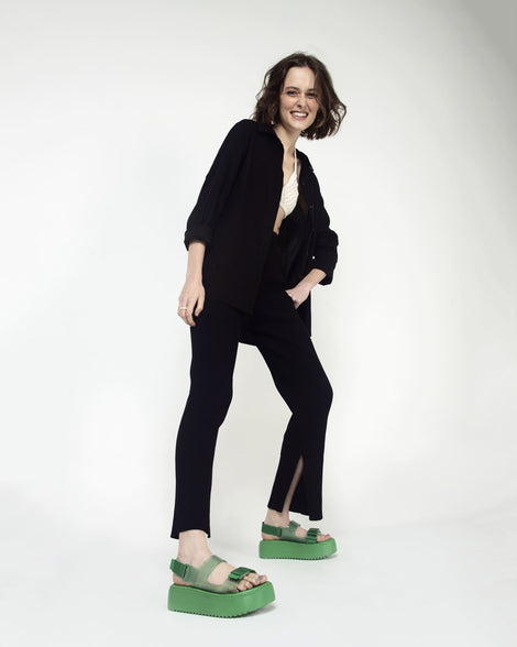 A model  posing for a picture wearing a pair of green Melissa's Brave Papete Platform sandals. 