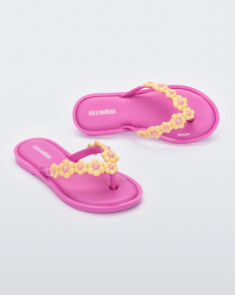 A top and side view of a pair of lilac Mini Melissa Spring Flip Flops with yellow and pink flowers.