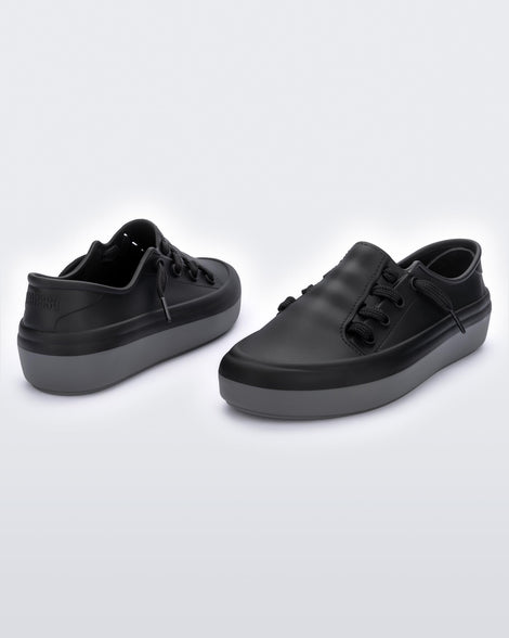 An angled front and back view of a pair black Melissa Ulitsa sneakers with a black base, laces and a gray sole.