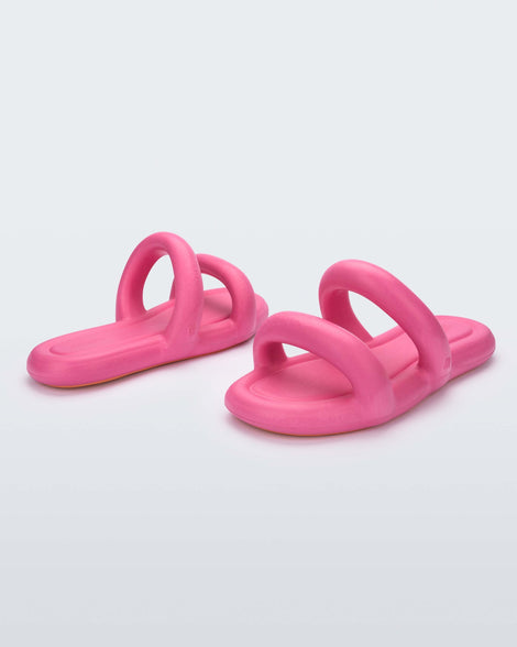 An angled side and front view of a pair of pink Melissa Free Bloom Slides with puffer-like straps.