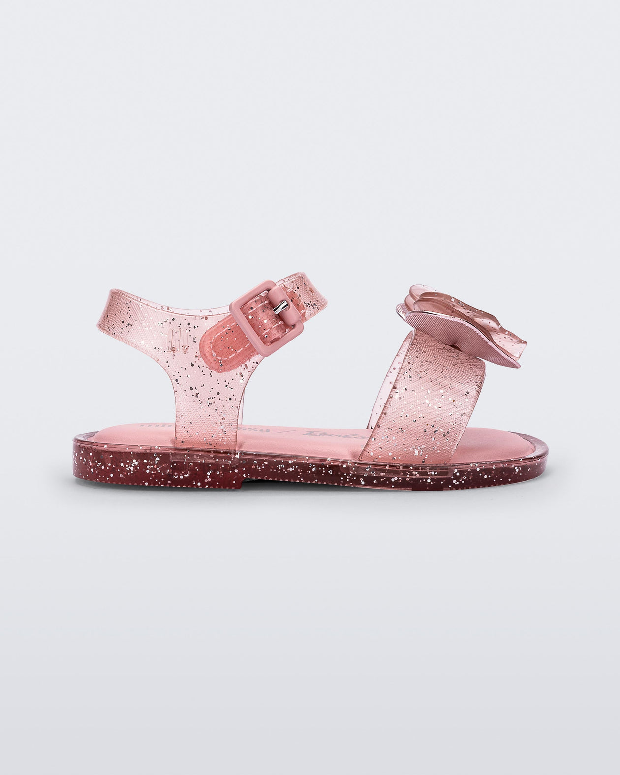 Side view of a pink glitter Mini Melissa Mar Sandal with a pink heart shaped bow and buckle.