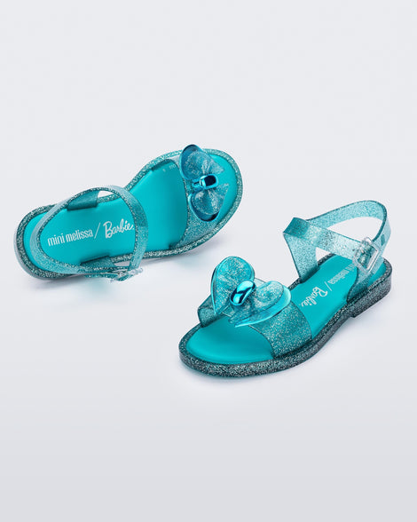 Angled view of a pair of blue glitter Mini Melissa Mar sandals with bows.