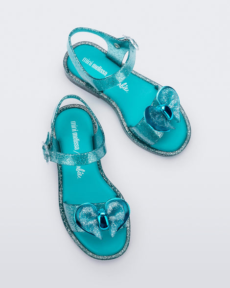 Top view of a pair of blue glitter Mini Melissa Mar sandals with bows.