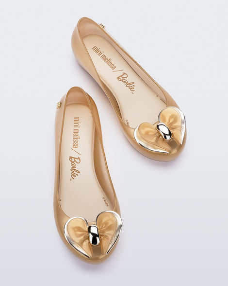 Top view of a pair of Pearly Beige Mini Melissa Ultragirl flats with a heart buckle bow detail on the toe.