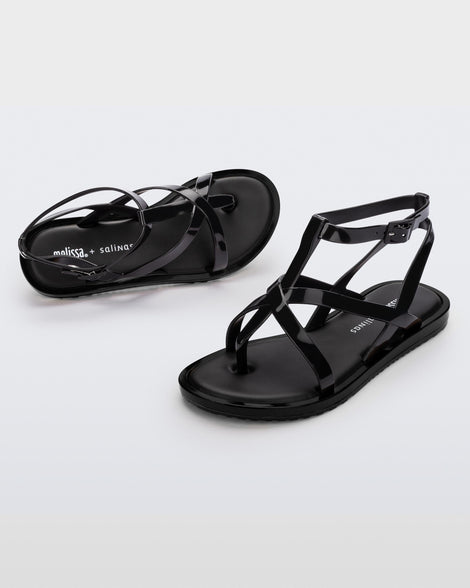 An angled front and side view of a pair of black Melissa Cancun sandals with several straps.