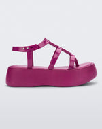 Side view of a pink Melissa Caribe High Platform sandal with two pink front straps joined by a vertical strap intersecting the ankle strap and a black sole.