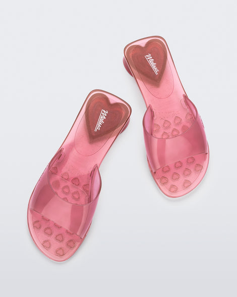 Top view of a pair of tranparent pink Melissa Kim slides.