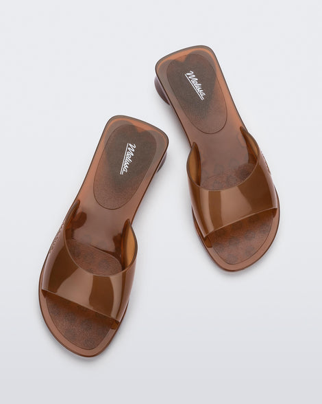 Top view of a pair of transparent brown Melissa Kim slides.