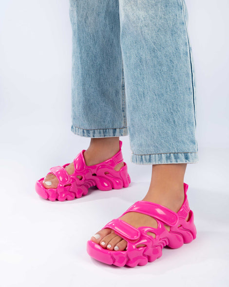 Close up of a model's legs wearing a pair of Melissa Puff chunky sandals in pink with velcro straps