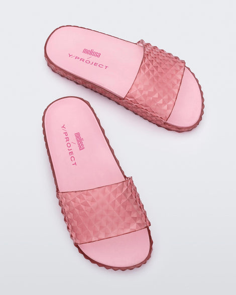 Top view of a pair of transparent pink Melissa Court Slides with a checkered pattern texture.