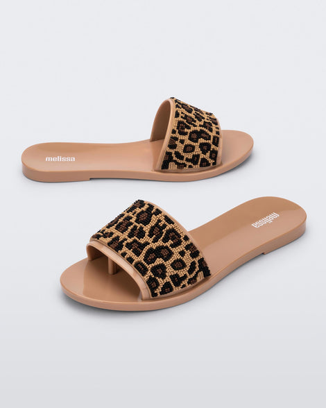 An angled side view of a pair of beige/black Melissa Savage slides with a cheetah print top strap.