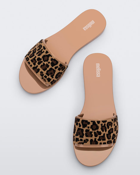 A top view of a pair of beige/black Melissa Savage slides with a cheetah print top strap.