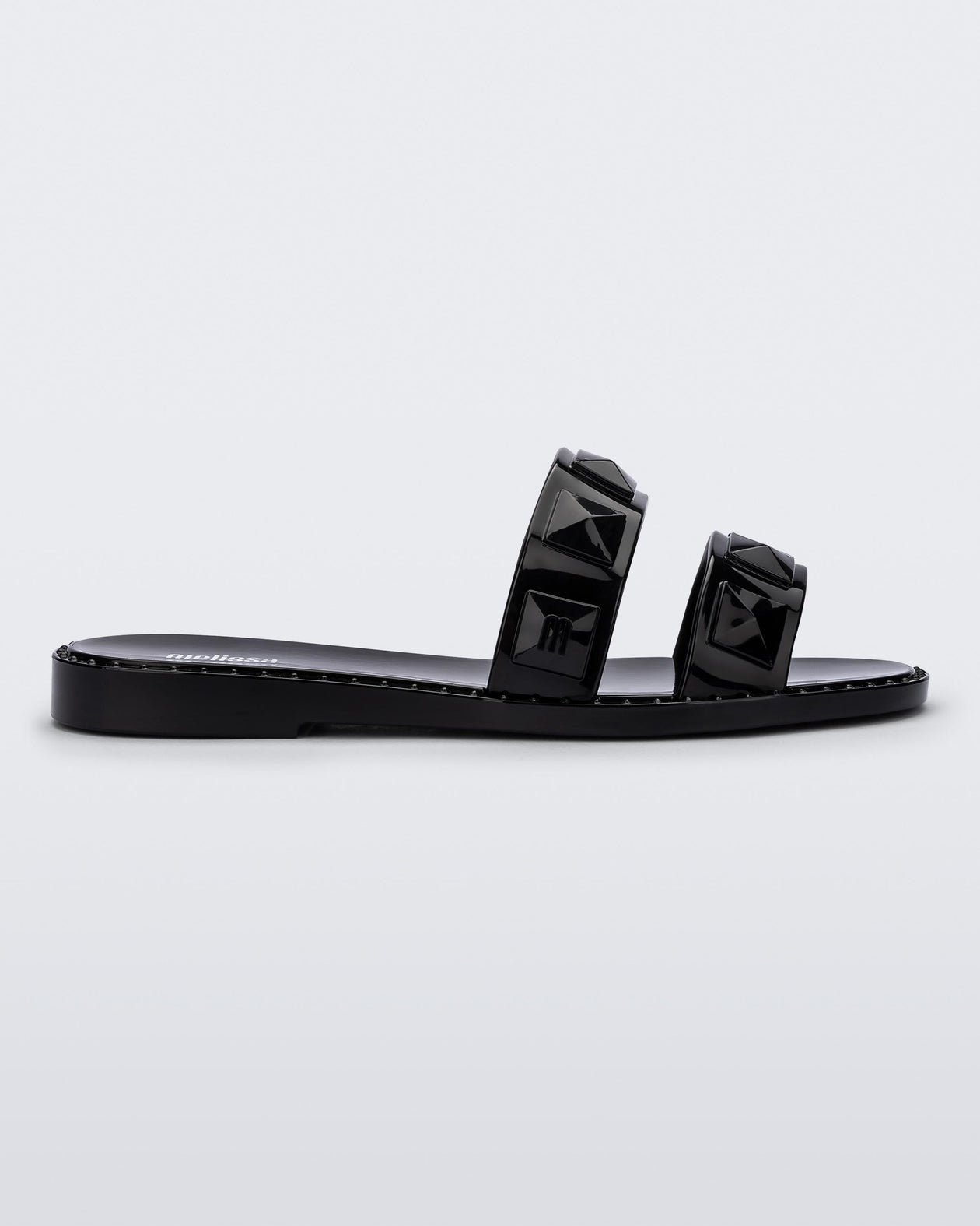 Side view of a black Melissa Lucy slide with stud details on the two straps.