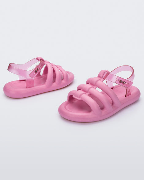 An angled back and front view of a pair of pink Melissa Freesherman sandals with pink and clear straps.