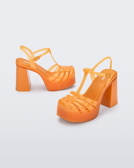 A side view of a pair of orange Melissa Party Heels with several straps and a closed toe front.