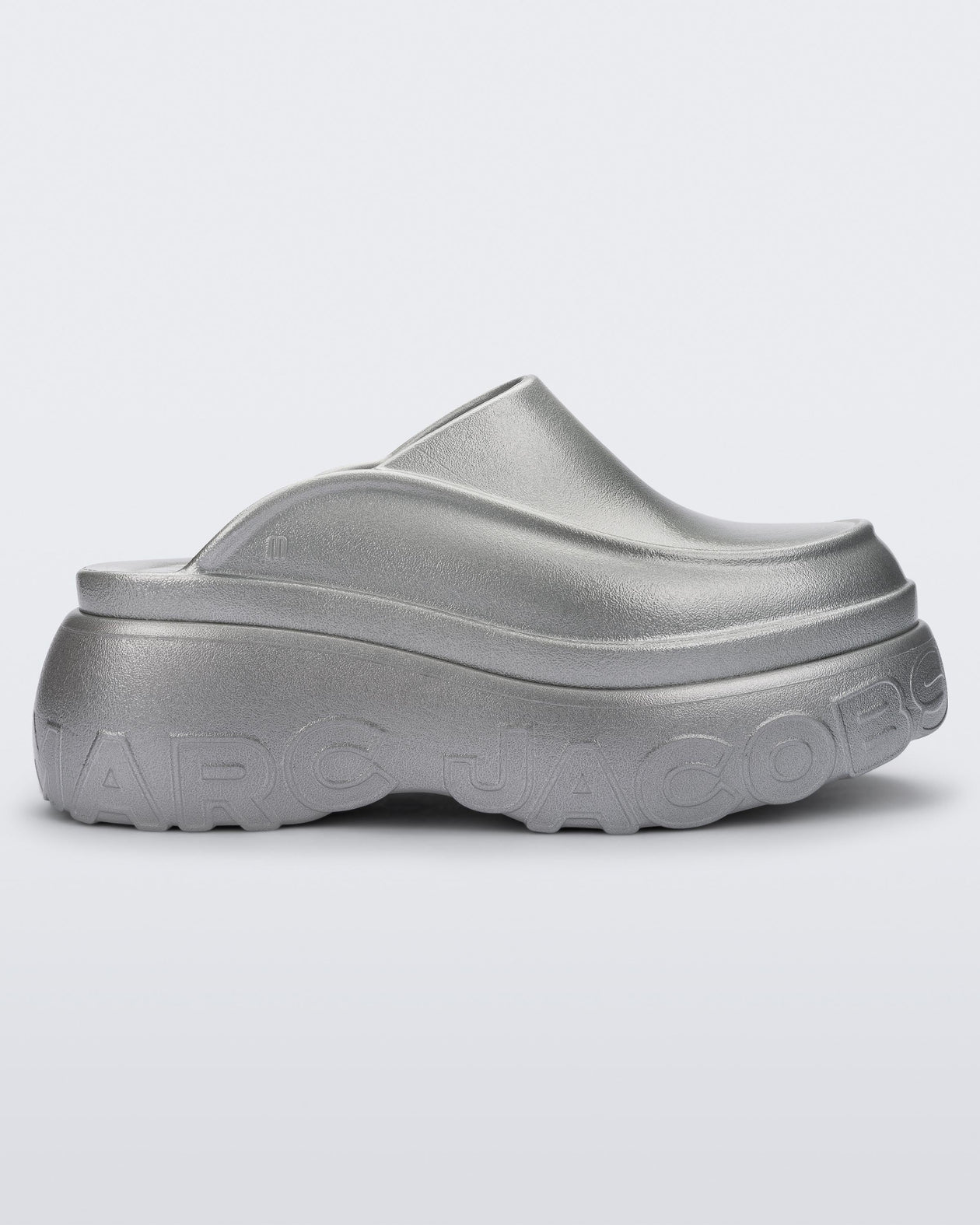 Side view of a silver Melissa Clog with the Marc Jacob's logo across the sole.