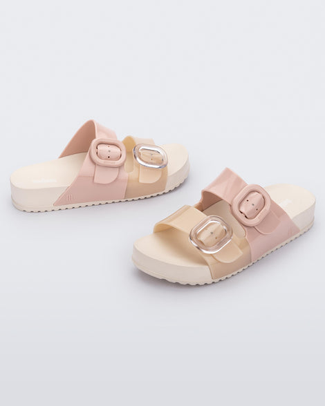 A side view of a pair of Beige/Pink Melissa Cozy slides with two pink and beige straps with a buckle detail.