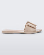 An outter side view of a Beige Melissa Babe slide with a buckle like bow detail on the front strap.