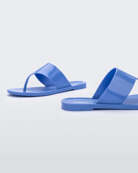 Font and back angled view of a a pair of Melissa Essential Chic flip flops in Opaque Blue with thick thong straps