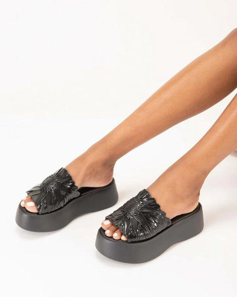 A model's legs wearing black Melissa Panc Becky platform sandals.
