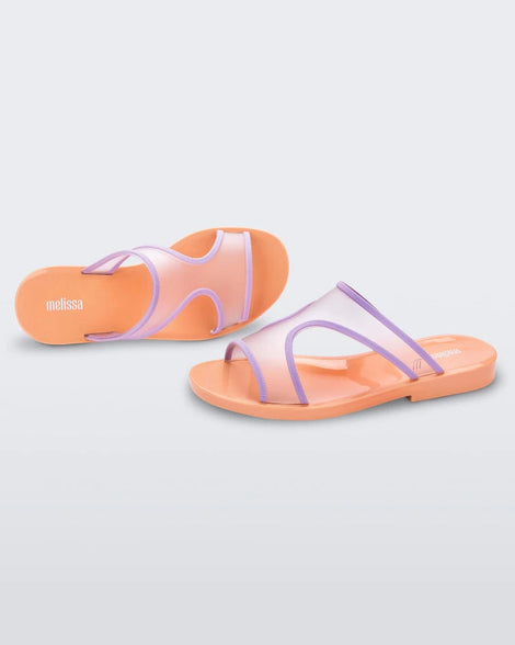 A side and top view of a pair of orange/lilac Melissa Bikini Slides with a two transparent purple straps conjoining in the middle and an orange insole.