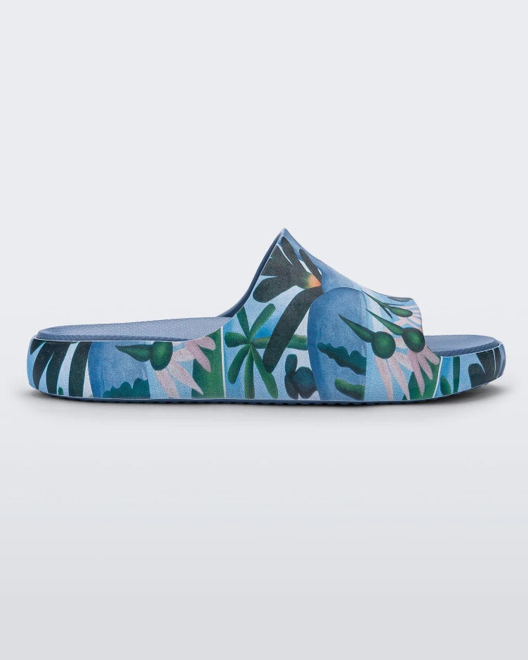 Side view of a blue multicolor Melissa Cloud slide with an abstract painting design of plants, water and lagoon.