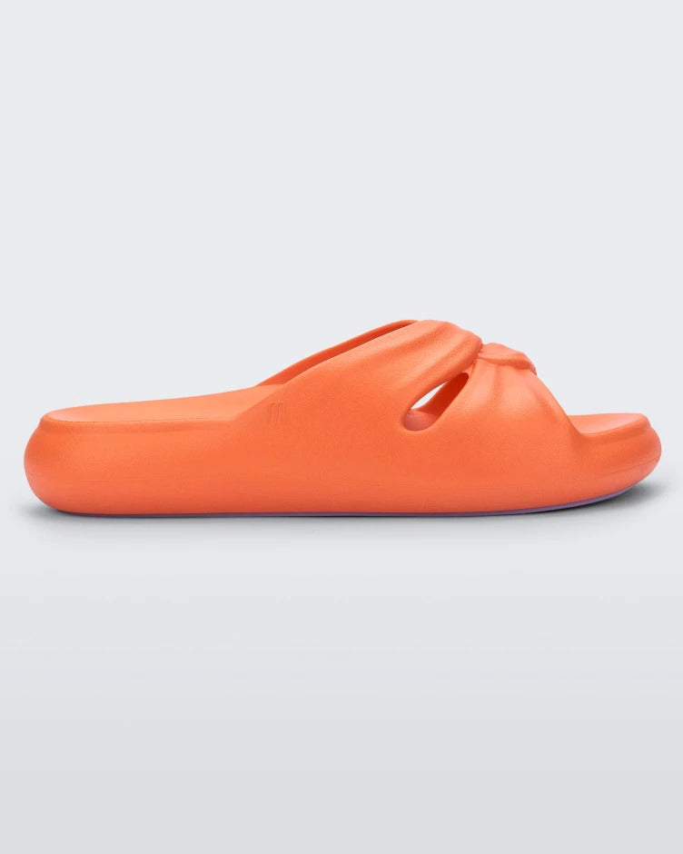 Side view of an orange Melissa Free Slide sandal in orange with a twist front detail.