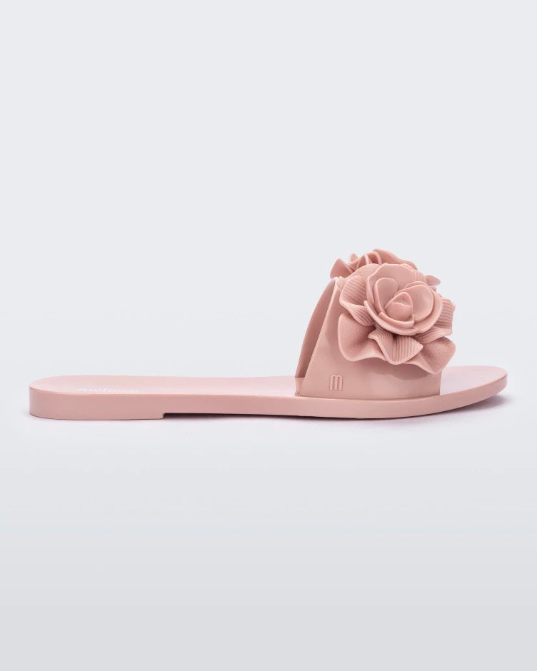 Side view of a light pink Melissa Babe Garden slide with two flowers on the front strap.