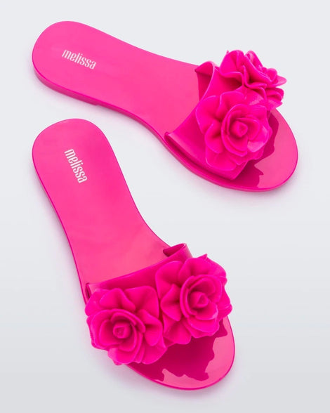 Top view of a pair of neon pink Melissa Babe Garden slides with two flowers on the front strap.